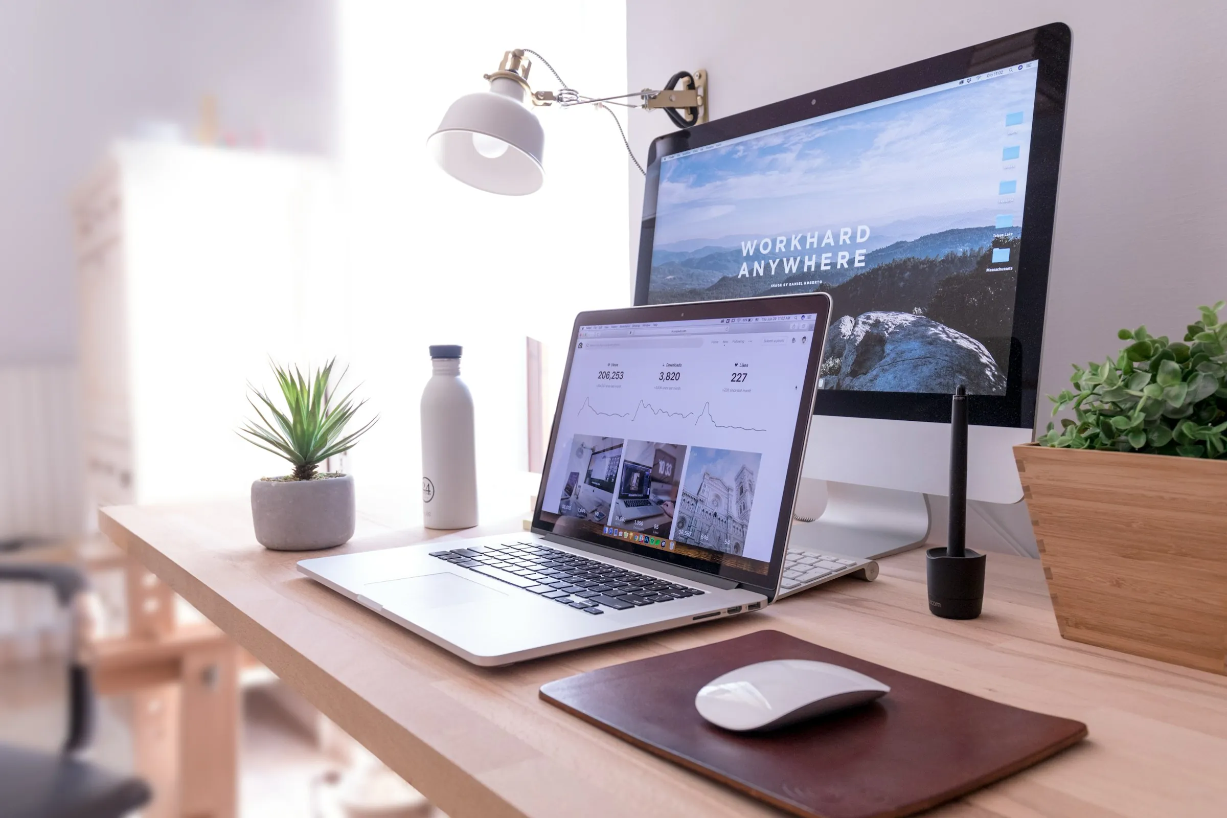 Bright desk with an iMac, laptop and plants